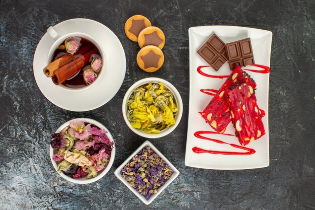 Free Photo overhead view of herbal tea with chocolate on white plate with dry flowers on grey ground