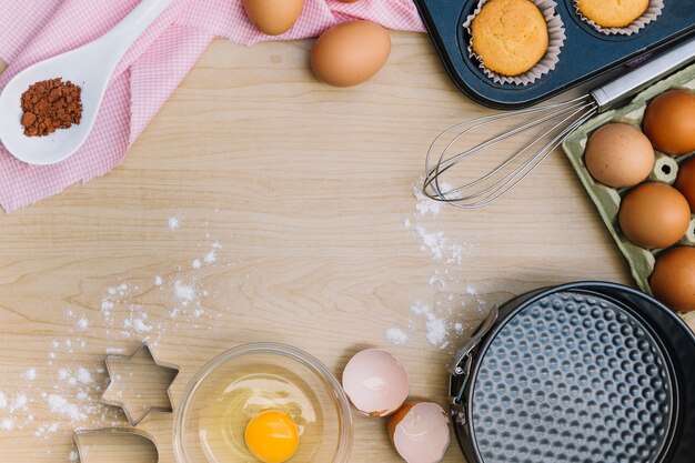 An overhead view of homemade cupcake and ingredients on wooden desk