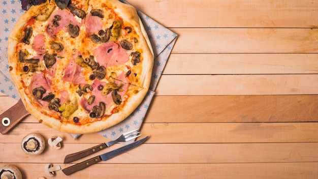 An overhead view of homemade pizza with mushroom on wooden table