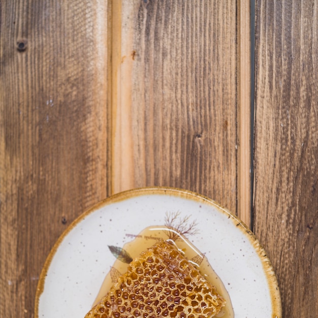 Free Photo an overhead view of honeycomb on plate over wooden backdrop