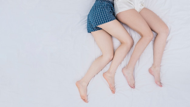 Free Photo an overhead view of lesbian couple's legs on white bed