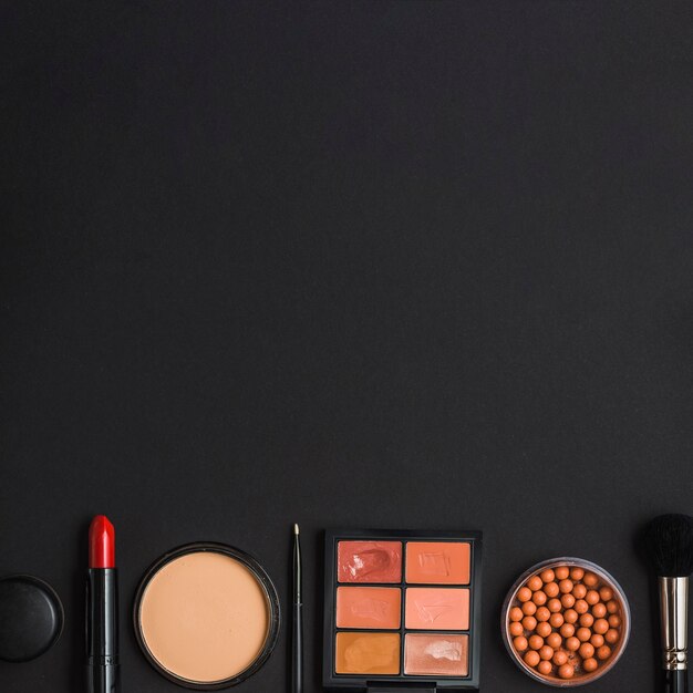 Overhead view of makeup products at the bottom of black backdrop