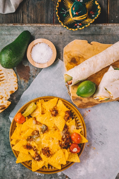 Free photo overhead view of mexican nachos tortilla chips; lemon; avocado on rusty background