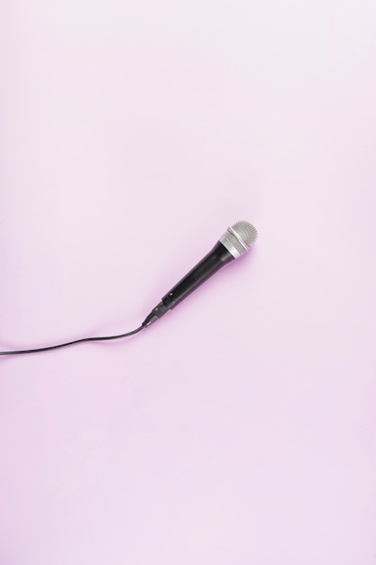 An overhead view of microphone on pink background