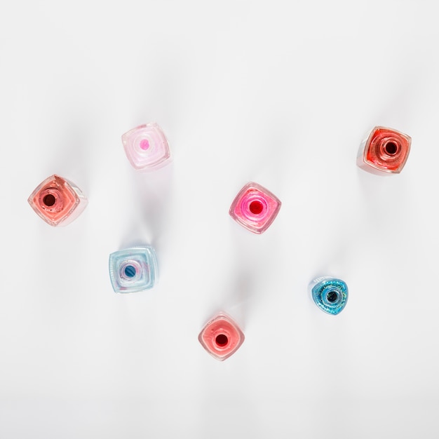 Free photo overhead view of multi colored nail polish bottles on white background