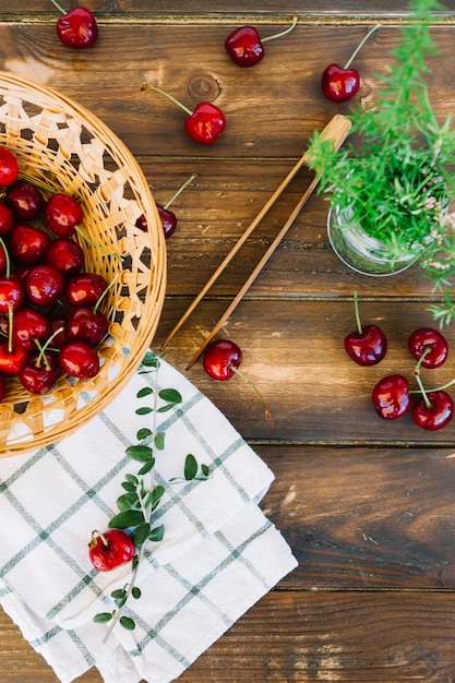 Free Photo overhead view of napkin; rosemary and red cherries in wicker bowl