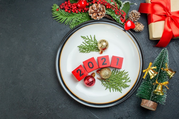 Overhead view of numbers decoration accessories on a plate fir branches conifer cone on the left side on dark background