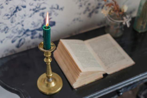 Free Photo an overhead view of an open book and lighted candle on desk