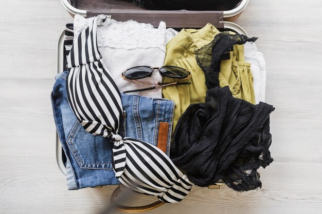 Overhead view of open traveler's bag with outfits and accessories