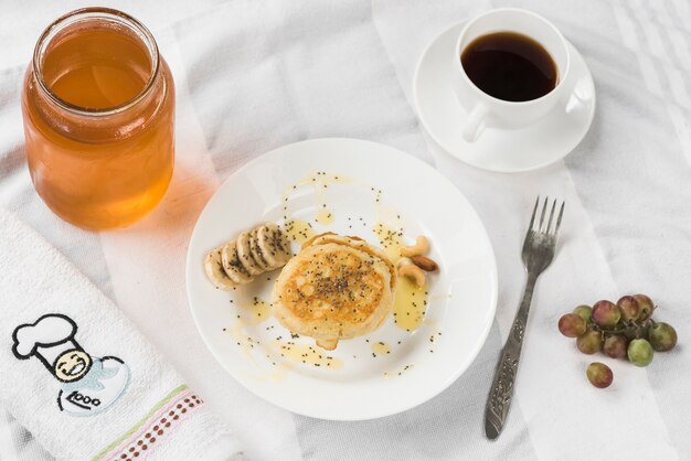 An overhead view of pancake with honey; banana slices and chia seeds on plate