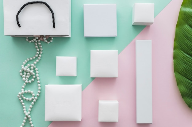 Free Photo overhead view of pearls necklace with many white boxes on paper backdrop