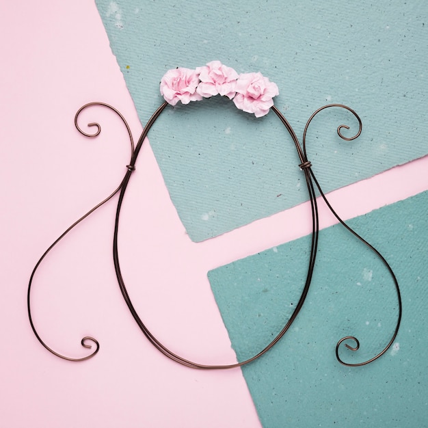 An overhead view of pink roses over the oval frame on paper against pink backdrop