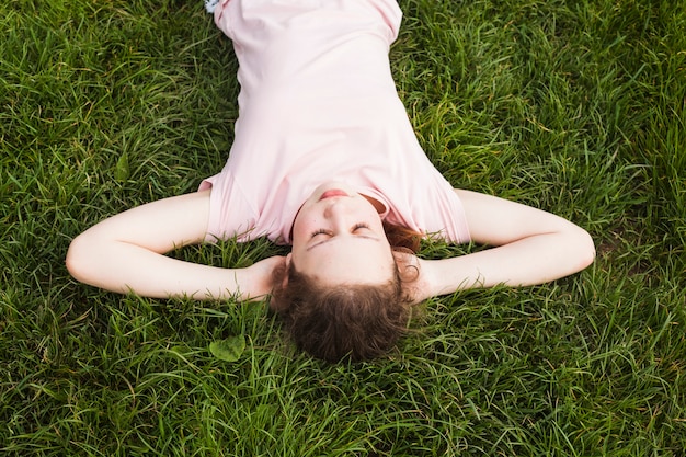 Free photo overhead view of pretty girl lying on grass in park