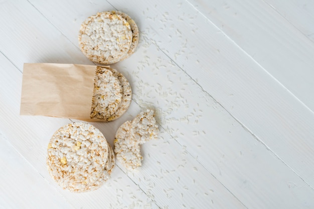 An overhead view of puffed rice with grains on white wooden desk