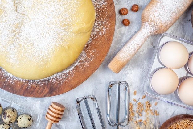 Overhead view of raw pastry flour on round board grater eggs on stained white background