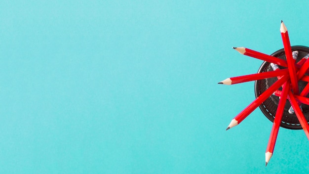 Free photo an overhead view of red pencils in the holder against turquoise background