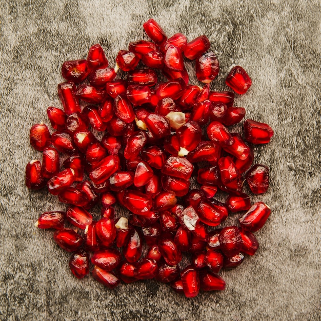 An overhead view of red pomegranate seeds on grunge background