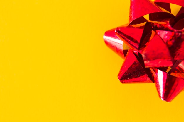 Overhead view of red ribbon bow on yellow background