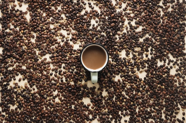 Free photo an overhead view of roasted coffee beans and coffee cup