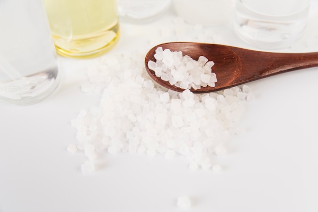 Free photo an overhead view of rock salts on wooden spoon against white backdrop