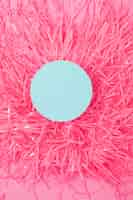 Free photo an overhead view of round frame on pom pom against pink background