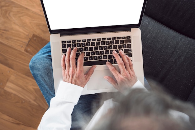 Free photo an overhead view of senior man typing on laptop