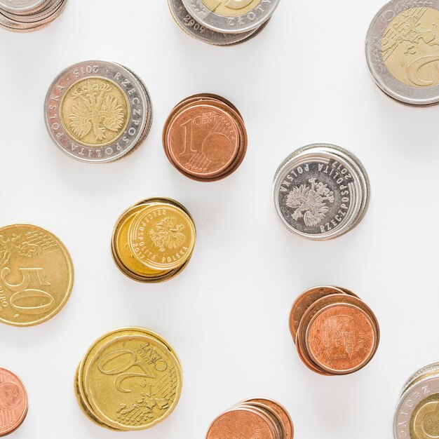 An overhead view of silver; gold; and copper coins on white background