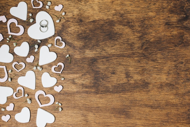 An overhead view of silver wedding rings on heart shape over the wooden backdrop