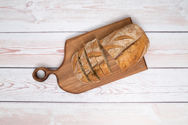 An overhead view slices of bread on chopping board over the wooden plank background