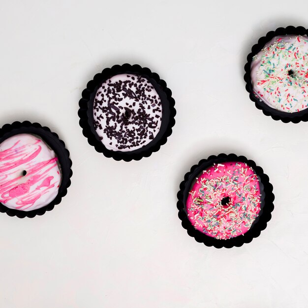 An overhead view of small donuts in brown paper holder against white background