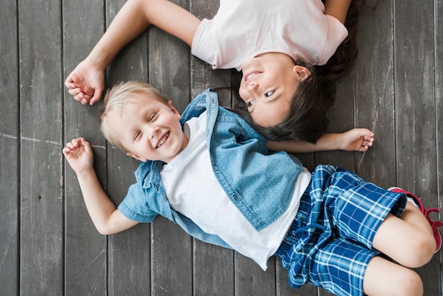 Free Photo an overhead view of smiling boy and girl lying on hardwood floor