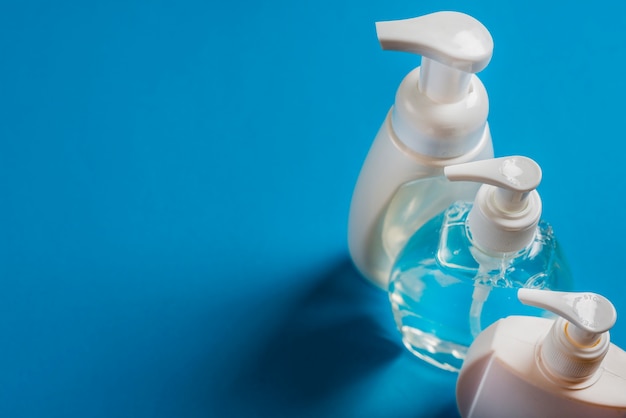 An overhead view of soap dispenser bottles on blue backdrop