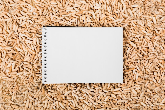 Free photo an overhead view of spiral white notepad over the brown puff rice