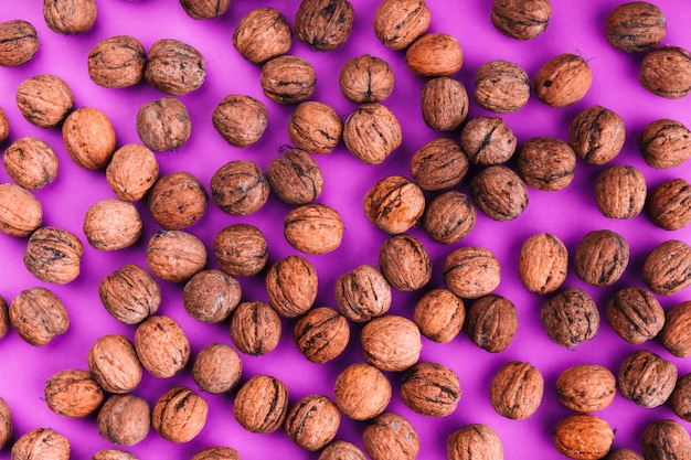 Free Photo an overhead view of spread walnuts on pink background