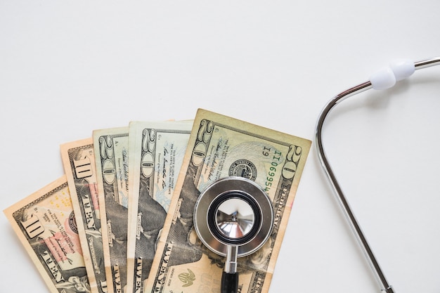 Overhead view of stethoscope on us currency note over white background