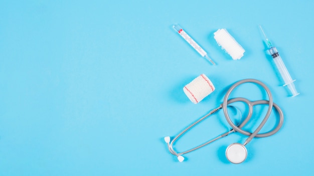 Free photo overhead view of stethoscope with medical equipments on blue background