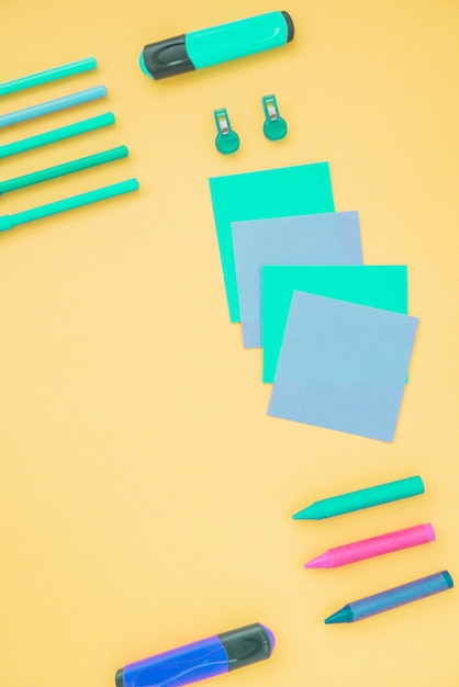 Free Photo overhead view of sticky note; highlighter and crayons on yellow background