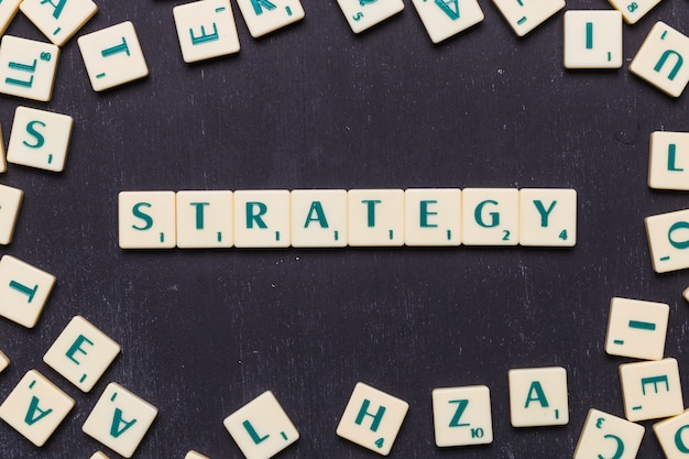 Free photo overhead view of strategy text on scrabble letters over black backdrop