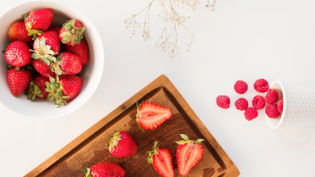 Free photo an overhead view of strawberries; and raspberries with gypsophila flower isolated on white background