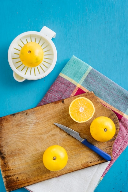 Free photo overhead view of sweet limes and manual juicer on blue surface