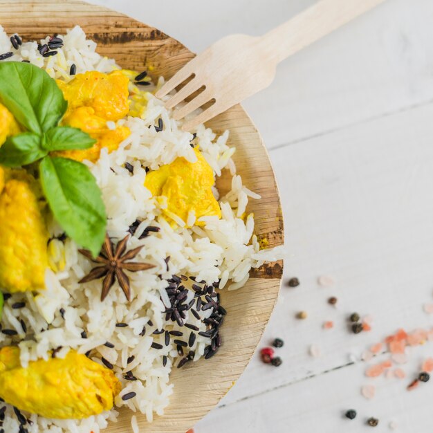 Overhead view of tasty chicken and rice in plate with basil leaves