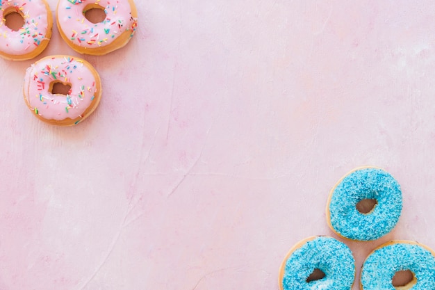 Overhead view of tasty donuts on pink backdrop