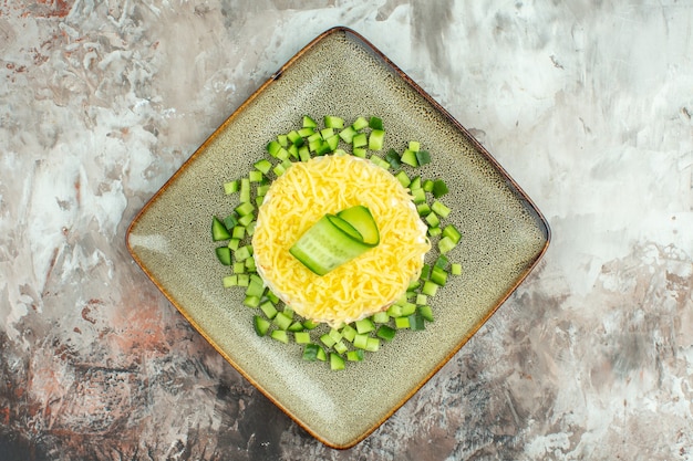 Free Photo overhead view of tasty salad served with chopped cucumber on mixed color background