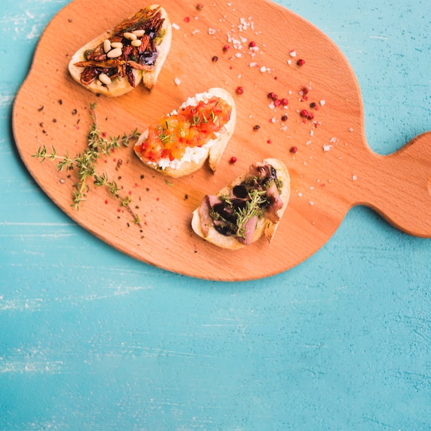 Free Photo an overhead view of toasted sandwiches with thymes; peppercorn and salt on chopping board