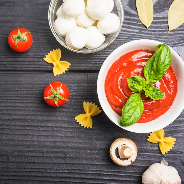 An overhead view of tomato sauce with mozzarella; pasta; mushroom and garlic