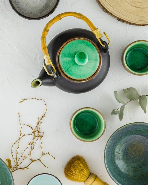 An overhead view of traditional chinese tea set with brush on white textured backdrop