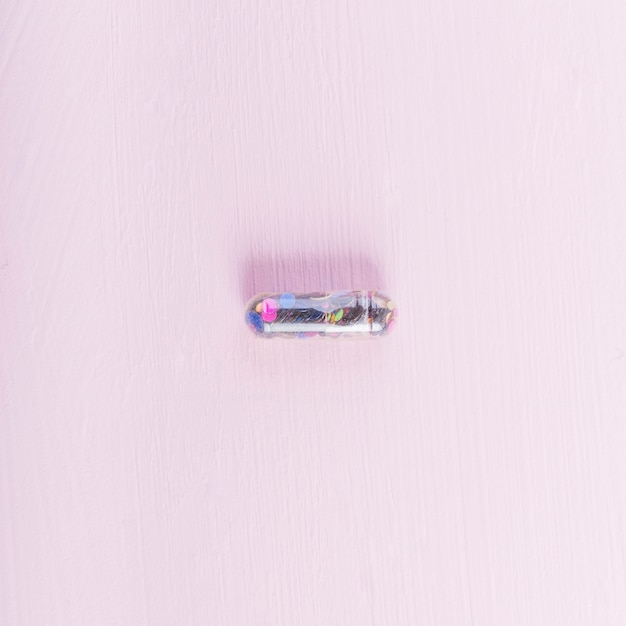 Free Photo overhead view of transparent sequin capsule on pink backdrop