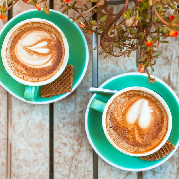 An overhead view of two coffee cup with heart shape latte art