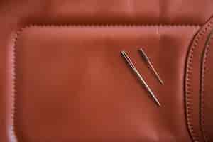 Free photo an overhead view of two needles on brown leather