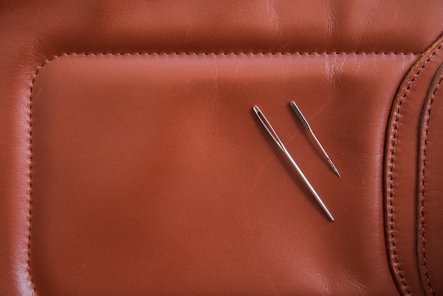 An overhead view of two needles on brown leather